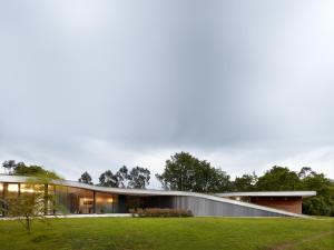 a modern house with glass windows and a lawn at CAEaCLAVELES in La Pereda de Llanes