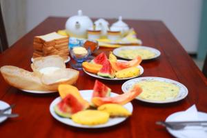 una mesa de madera cubierta con platos de pan y fruta en Sajana Ocean Hill, en Mirissa