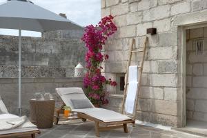 um par de cadeiras e um guarda-sol num pátio em Corte Dei Granai em Maglie
