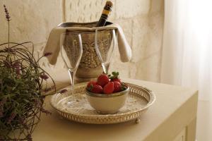 a table with a bowl of strawberries and a bottle of wine at Corte Dei Granai in Maglie