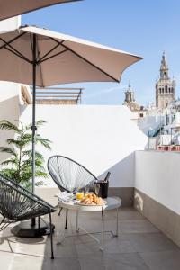 Una mesa y una silla en un balcón con una sombrilla. en Oak & Sandstone Studio - Space Maison Apartments, en Sevilla
