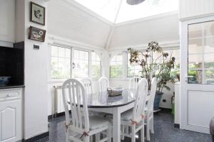 a dining room with a table and white chairs at Maison de Maître meulière in Neuilly-Plaisance