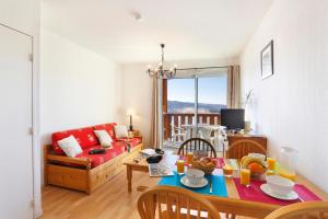 a living room with a table and a red couch at Résidence Néméa Les Chalets Du Belvédère in Font-Romeu