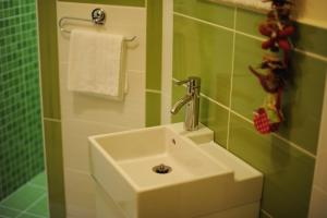 a white sink in a bathroom with green tiles at Apartments Life & Energy in Čatež ob Savi