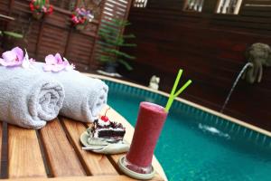 una fetta di torta e un drink su un tavolo accanto alla piscina di Rich Lanna House a Chiang Mai