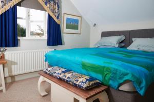 a bedroom with a bed with blue sheets and a bench at Tallow House in Ludlow
