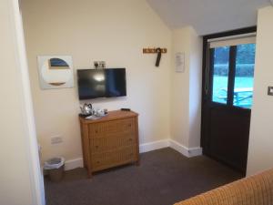 um quarto com uma televisão e uma cómoda em madeira com uma janela em The Duke William Bed and Breakfast em Harleston
