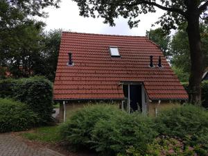 ein Haus mit einem roten Dach mit einer Tür in der Unterkunft Vakantiepark Timmerholt in Westerbork