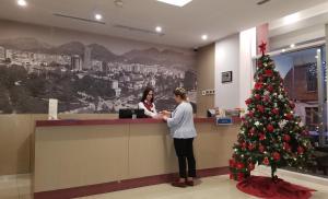 Dos mujeres de pie en un mostrador con un árbol de Navidad en Sky 2 Hotel Tirana en Tirana