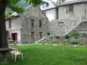 an old stone building with a chair in a yard at Maison Fouga in Cadéac +18 photos