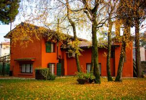 バッサーノ・デル・グラッパにあるCa' Boschettoの目の前に木々が生い茂るオレンジの家