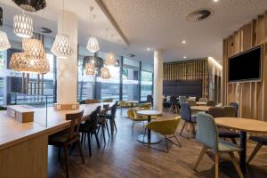 a restaurant with tables and chairs and windows at Citadines Arnulfpark Munich in Munich