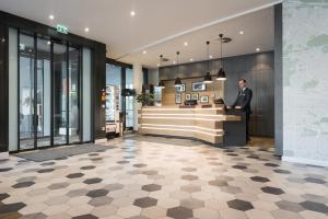 a man standing at a counter in a lobby at Citadines Arnulfpark Munich in Munich