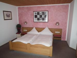 a bedroom with a bed with a pink wall at Waldgasthof - Hotel Schiederhof in Wiesenfelden