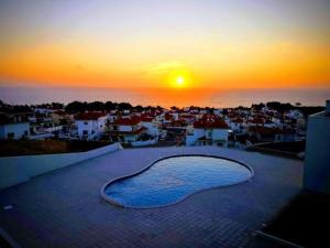 - une vue sur le coucher de soleil sur une ville avec piscine dans l'établissement Marnix´s Apartment, à Nazaré