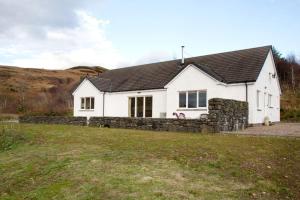 a white house with a stone fence in front of it at Skye View in Glenelg