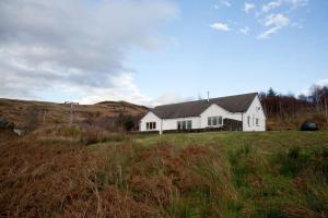 a white house in the middle of a field at Skye View in Glenelg