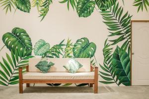 a bench in a room with a mural of leaves at Whalecome Aonang Resort-SHA Extra Plus in Ao Nang Beach