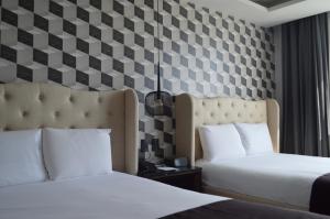 two beds in a hotel room with checkered walls at Casa Basalto in Pachuca de Soto