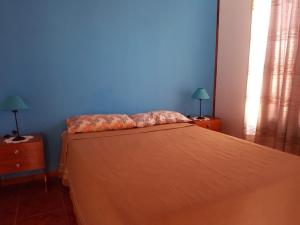 a bedroom with a bed with a blue wall at Las Casitas de Emilia in Ramallo