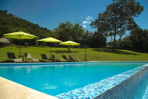 una piscina con sillas y sombrillas en Sauce Lodge - Laguna Azul, en Sauce