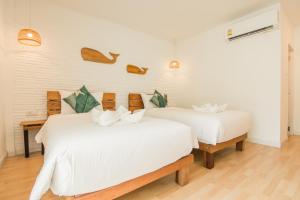 Habitación con 2 camas, paredes blancas y suelo de madera. en Whalecome Aonang Resort-SHA Extra Plus en Ao Nang Beach