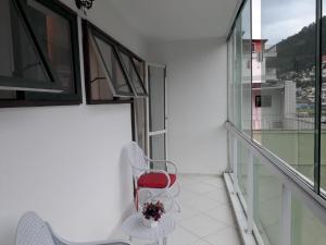 un balcón con 2 sillas y una silla roja en Apartamento Parque das Palmeiras, en Angra dos Reis