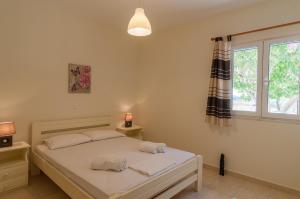 a bedroom with a bed with white sheets and a window at Felicia's sun-side house in Kastraki Naxou