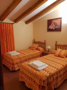 2 camas en una habitación con sábanas de color naranja en Casa Rural Barba, en Fuente-Higuera