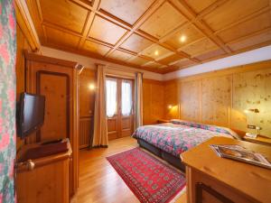 um quarto com uma cama e uma televisão de ecrã plano em Hotel Natale em Cortina dʼAmpezzo