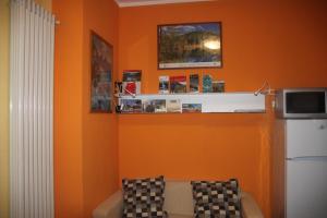 sala de estar con pared de color naranja y sofá en La Madonnina, en Villa di Tirano