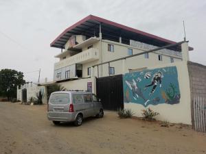 une camionnette garée devant un bâtiment avec une fresque murale dans l'établissement Auto Hostal Jaramisol, à Jaramijó