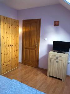 1 dormitorio con 1 cama y TV en un armario de madera en Kristály Apartmanház, en Sárvár