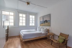 a white bedroom with a bed and two windows at Apartment Zentral im Herzen der Altstadt in Tübingen
