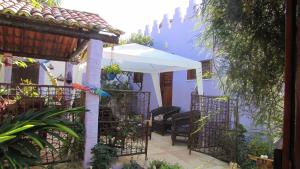 a patio with a white umbrella and chairs at Pousada da Lucinha in Canoa Quebrada
