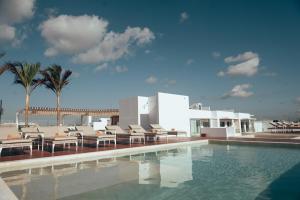 a swimming pool with chairs and a building at Antera Hotel & Residences in Playa del Carmen