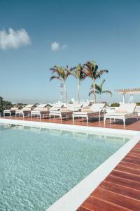 una piscina con tumbonas junto a la playa en Antera Hotel & Residences, en Playa del Carmen