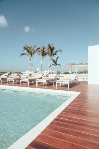a pool at the beach with chairs and palm trees at Antera Hotel & Residences in Playa del Carmen