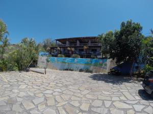 a building in the background with a stone patio at Pousada Akaroa in Búzios