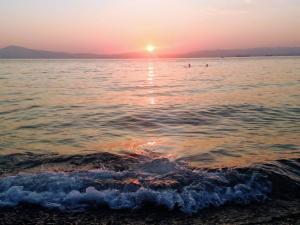 a sunset over the water with people in the ocean at SEMIRAMIS SUITES with pool and private jacuzzi in Kalamata