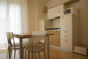 Aparthotel Royal في ليدو دي يسولو: مطبخ مع طاولة وكراسي وميكروويف