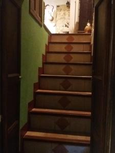 una escalera con escalones marrones en una sala verde en La Casa del Pittore di Petralia, en Petralia Soprana