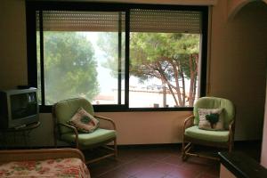 two chairs and a tv in a room with a window at Hotel Maristella in Cavo