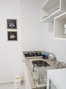 Una cocina blanca con un fregadero en una habitación. en Acácia Jurerê, en Florianópolis
