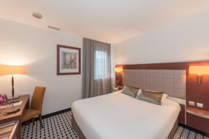 ein Hotelzimmer mit Bett und Schreibtisch in der Unterkunft Kyriad Limoges Centre Gare - Atrium in Limoges