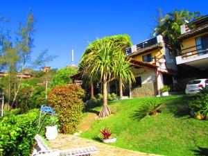 a house with a palm tree in a yard at Flat Geribá com linda vista, 500 metros da praia in Búzios