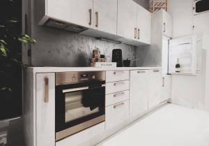 Una cocina con gabinetes blancos y un horno. en CASA GLITTER, en Liubliana 14 fotos más