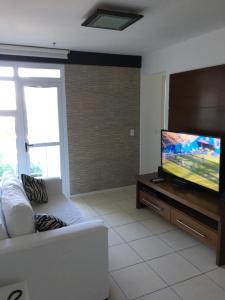 uma sala de estar com um sofá branco e uma televisão de ecrã plano em Apartamento linda vista, 200 metros da praia de camboinhas em Niterói