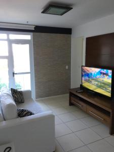 uma sala de estar com um sofá branco e uma TV de tela plana em Apartamento linda vista, 200 metros da praia de camboinhas em Niterói