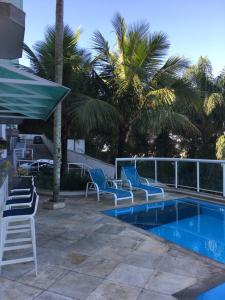 uma piscina com cadeiras azuis e palmeiras em Apartamento linda vista, 200 metros da praia de camboinhas em Niterói